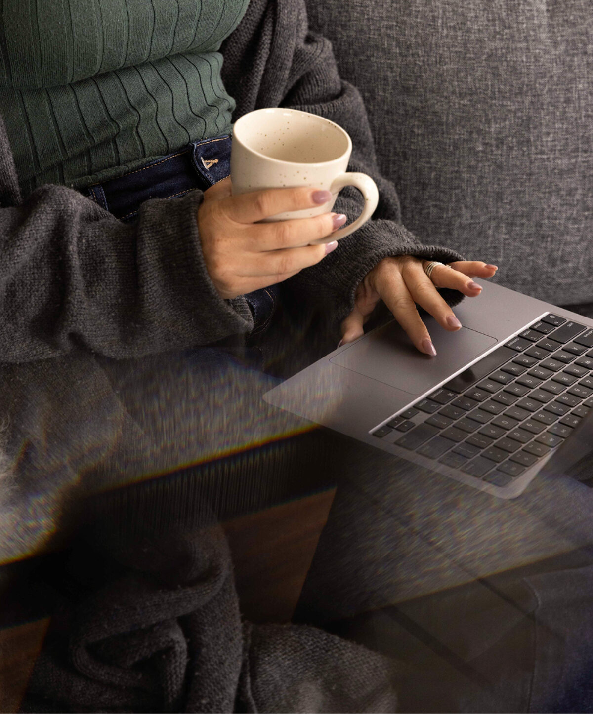 Person holding a coffee cup while browsing on a laptop