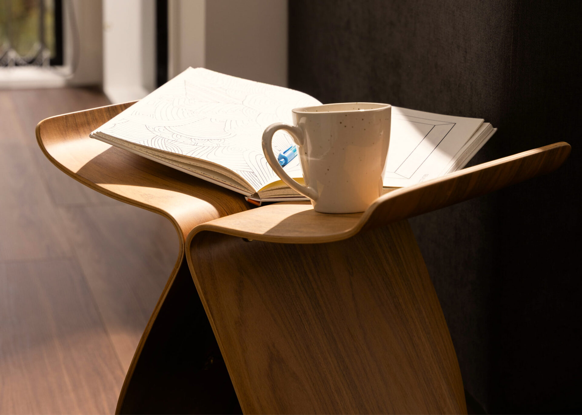 Open book and coffee cup resting on a wooden side table
