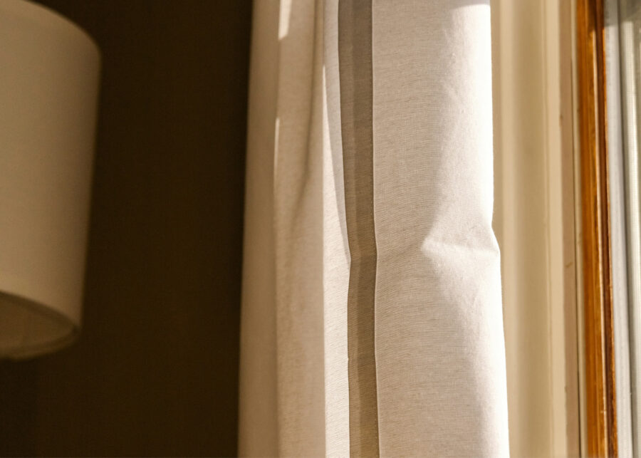 Soft light falling on linen curtains beside a lamp