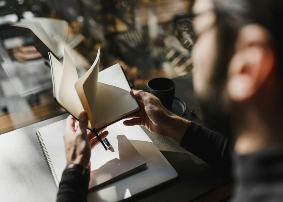 Man flipping through a book while holding a coffee cup